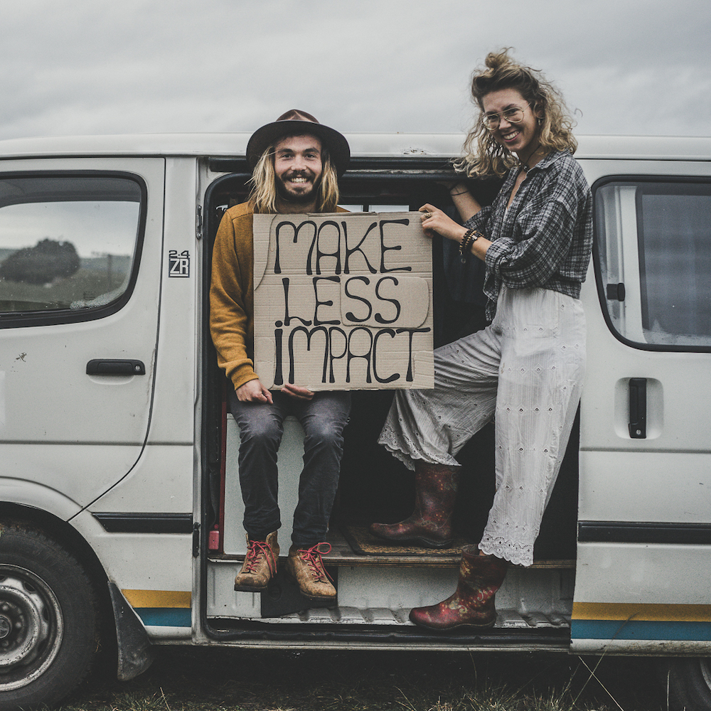 couple holds make less impact sign - responsible vanlife