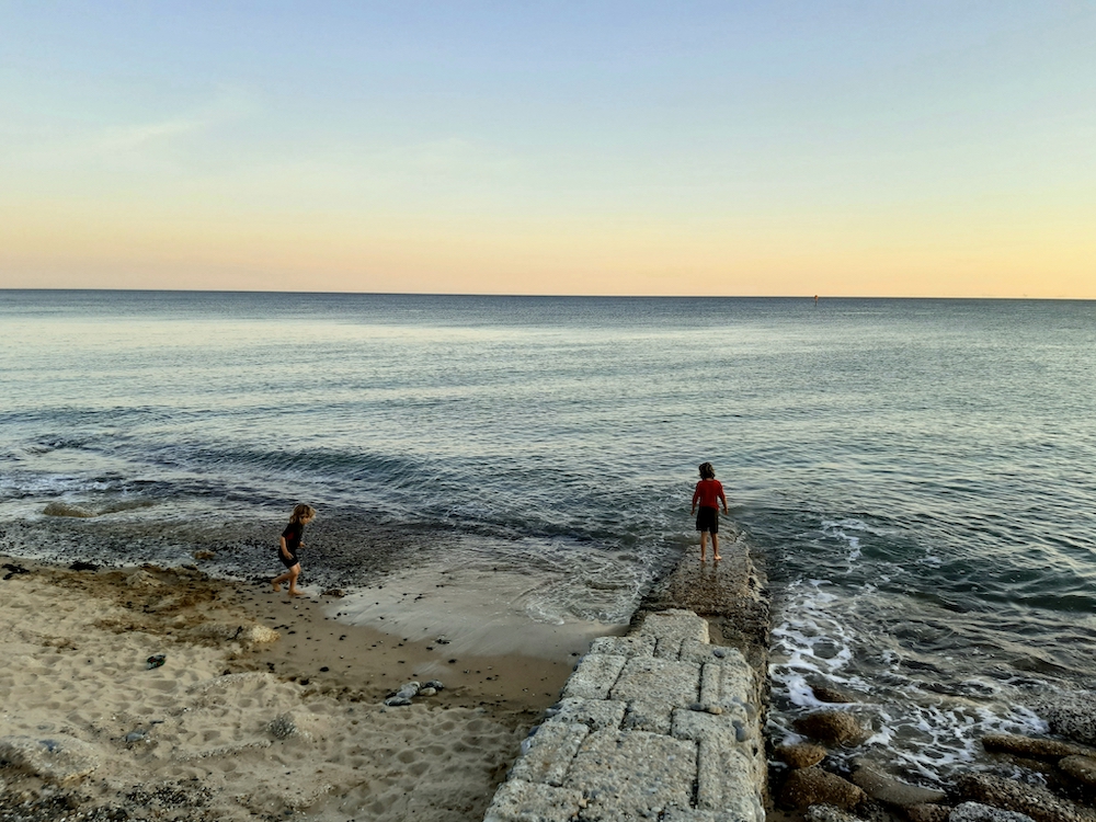 two kids playing at the shoreline - Isolation as a Traveler